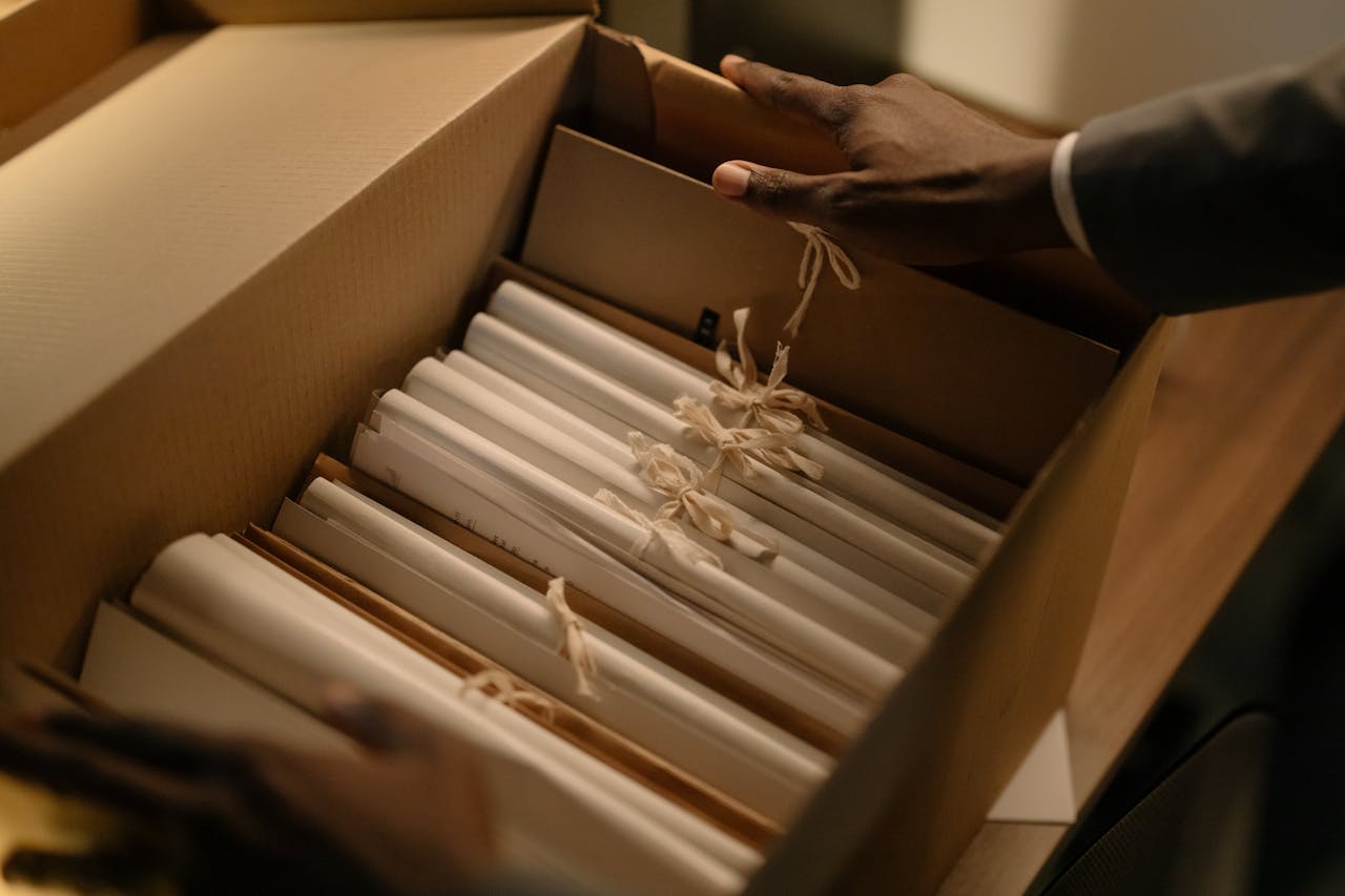 O Kancelarii Hands organizing files in a box, symbolizing investigation and research.
